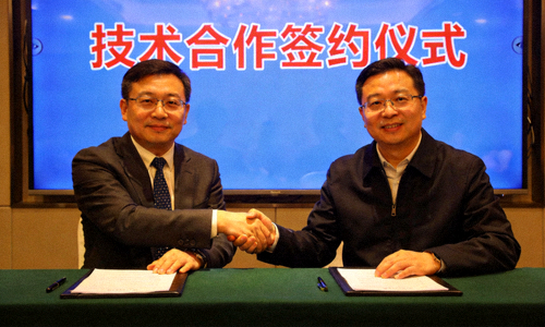 技术合作签约仪式现场，双方代表在蓝色背景板前握手合影